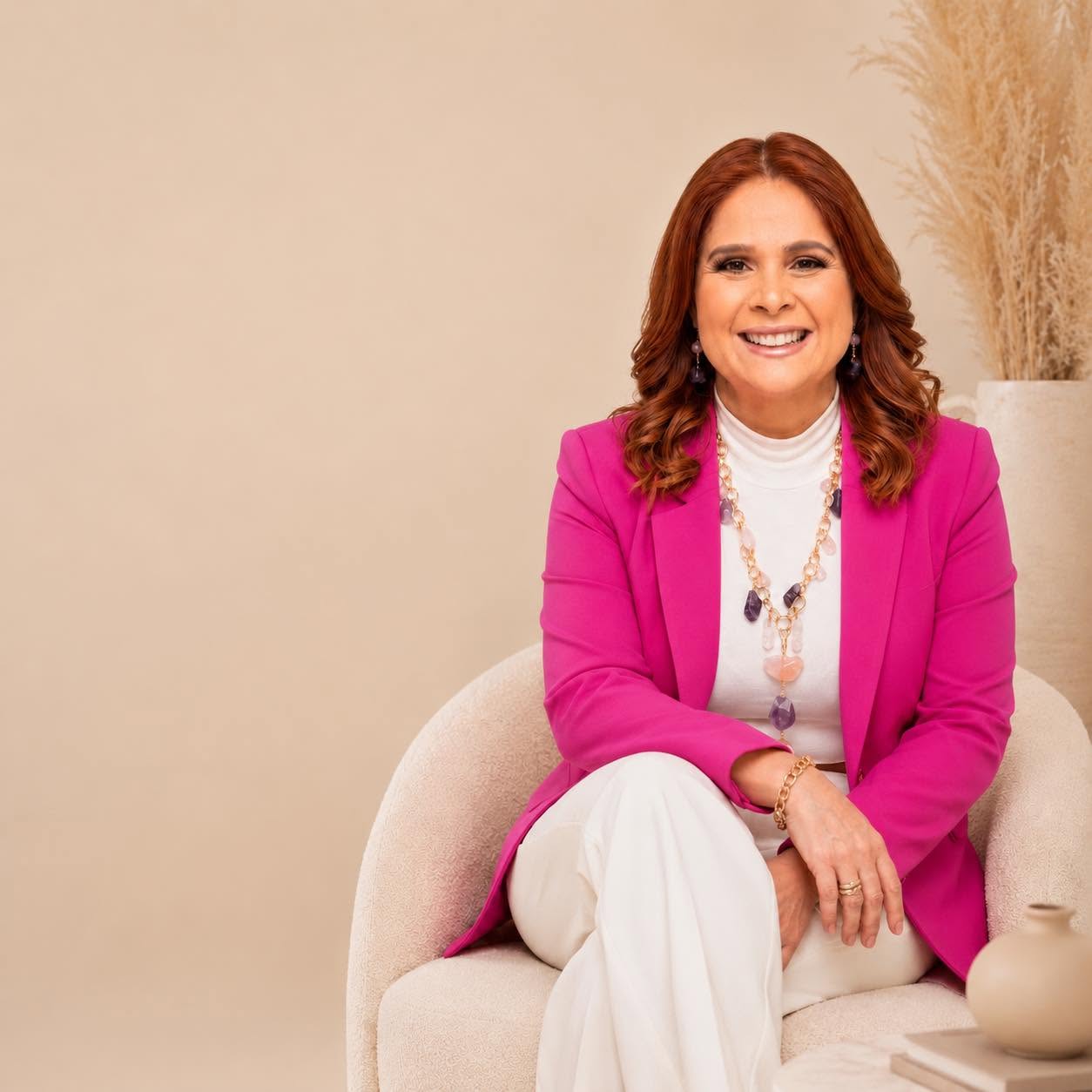 Madeline Rivera sentada, sonriendo, con blazer fucsia